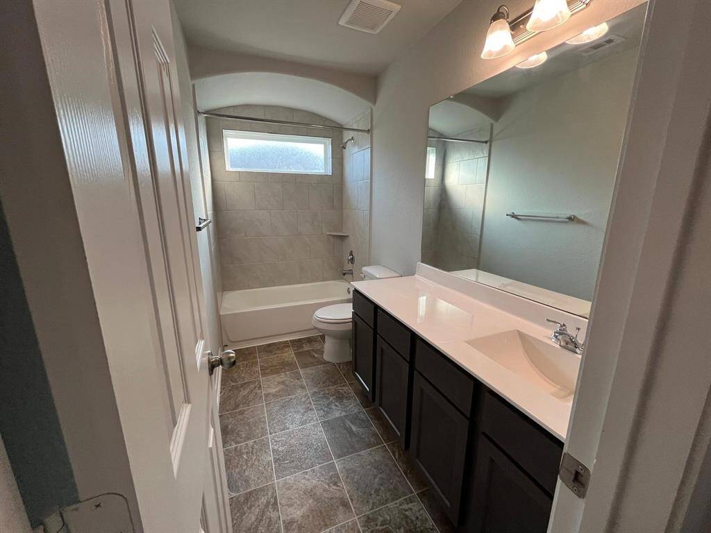 Secondary bathroom with floor to ceiling tiled wall and arched ceiling