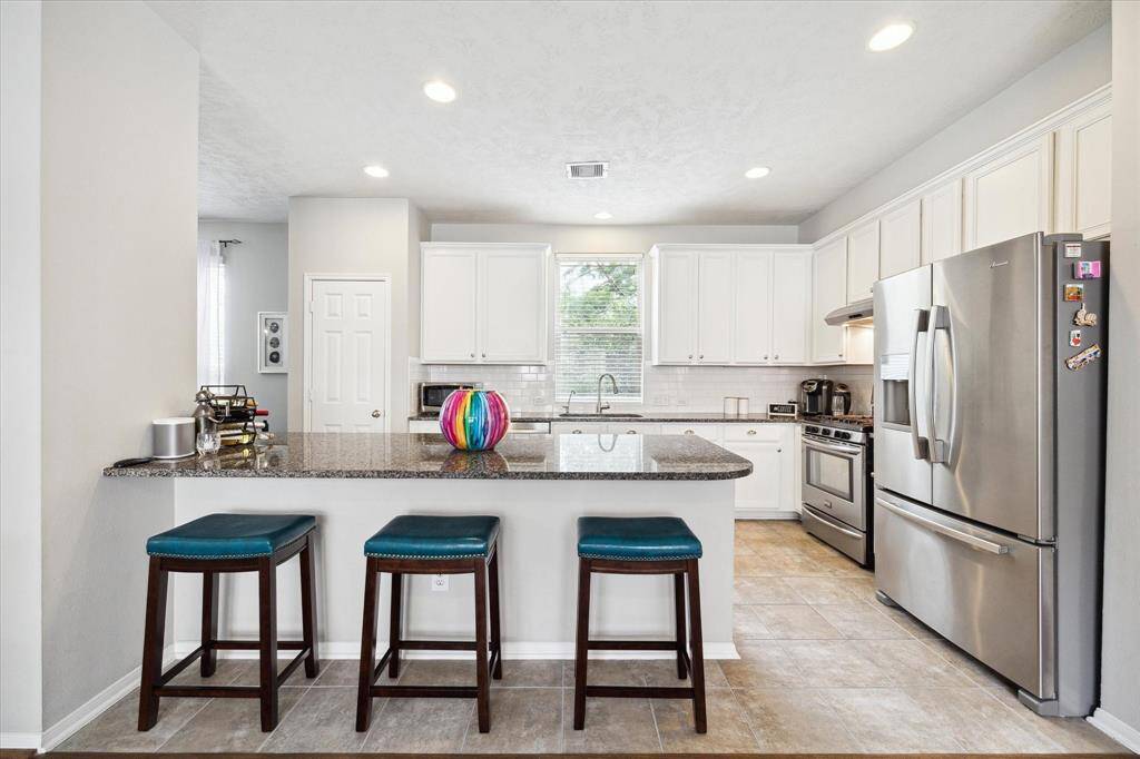 Another perspective of the kitchen showcasing the elegant breakfast island and the stylish subway tile backsplash.