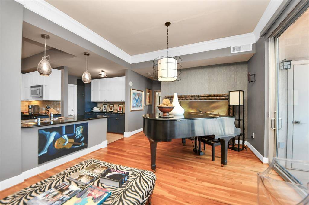 This stylish home features an open-concept living space with elegant hardwood floors and a modern kitchen with a breakfast bar. A grand piano adds sophistication to the living area, while large windows provide abundant natural light.