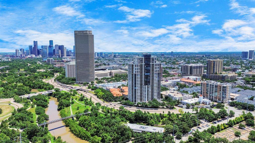 This photo showcases a vibrant cityscape with modern high-rise buildings surrounded by lush greenery and a winding river. The skyline is expansive, offering a mix of urban living and natural beauty, ideal for homebuyers seeking a dynamic yet scenic environment.