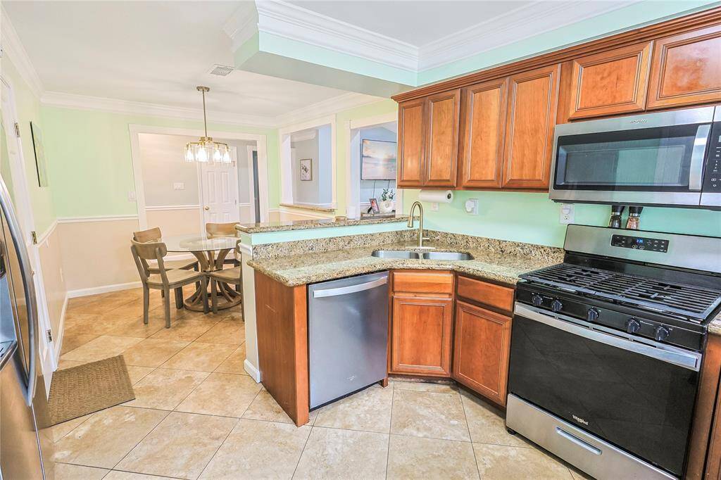 Another view of the kitchen showcasing the flow to the dining room and living areas. Equipped with fridge, dishwasher, gas-range stove and microwave- this kitchen has everything needed for your turn key living!