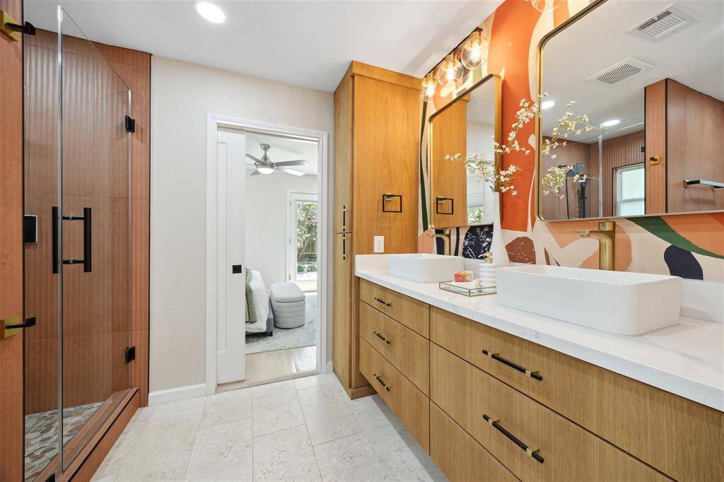 Primary bath newly remodeled in 2024 with custom oak cabinets , double sinks and frameless glass walk in shower