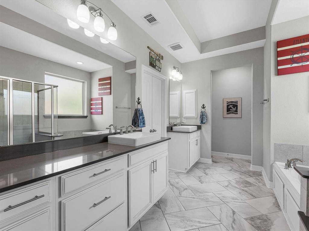 The en-suite bathroom offers a spa-like atmosphere with its elegant design, high end finishes, and tasteful lighting, creating a retreat within your own home.