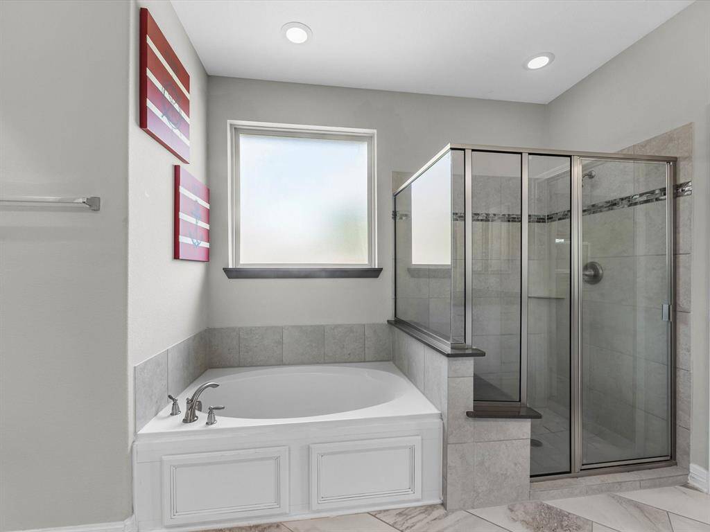 This additional view of your primary bathroom features tile flooring, fresh paint, walk-in shower, a separate garden tub, and a large walk-in closet.