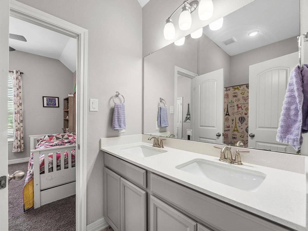 The secondary Jack and Jill bath features neural painted cabinetry and light countertops and a shower/tub combo.