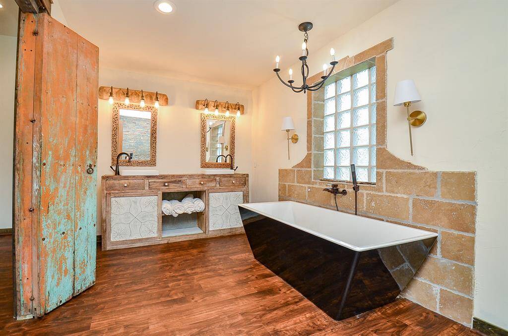 Another set of antique doors welcome you to the primary bath featuring soaking tub, large walk in shower and double vanities