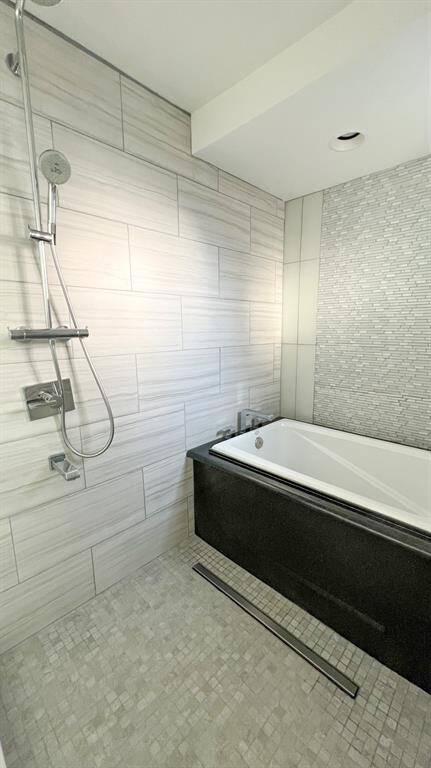 A view showcasing the primary bathroom, boasting an updated wet-room style shower and soaking tub.