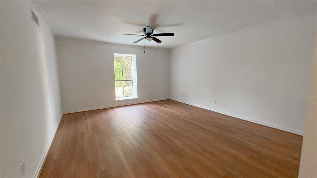 The secondary bedroom is adorned with wood flooring and oversized windows, creating an inviting retreat. Located on the first floor, this space is ideal for out-of-town guests.
