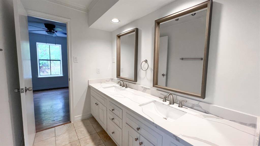 This secondary bathroom is located on the second floor and is shared by two of the upstairs bedrooms. Boasting dual sinks, updated quartz counters, coordinating designer mirrors, and recessed lighting.