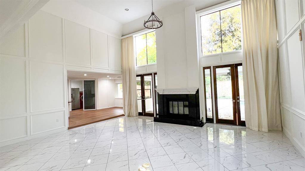 The stunning living room offers soaring ceilings and oversized windows that fill the room with natural light, creating the perfect space for gatherings. A granite fireplace serves as the focal point of the living room.