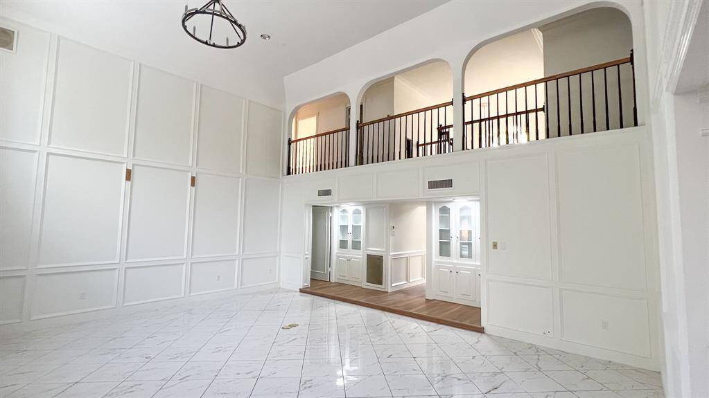 Another view of the living room showcases its high ceilings and wood detailing that makes it a wonderful setting for both lively gatherings and quiet evenings. The central location between the kitchen and living spaces creates an effortless flow for hosting and enjoying time with family.