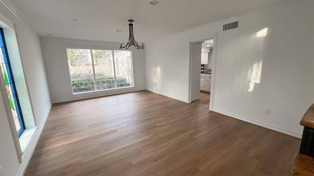 Gather in the formal dining room, where a midcentury-style chandelier anchors the space, complemented by large ornate windows that flood the room with abundant natural light, creating an inviting atmosphere for meals and gatherings.