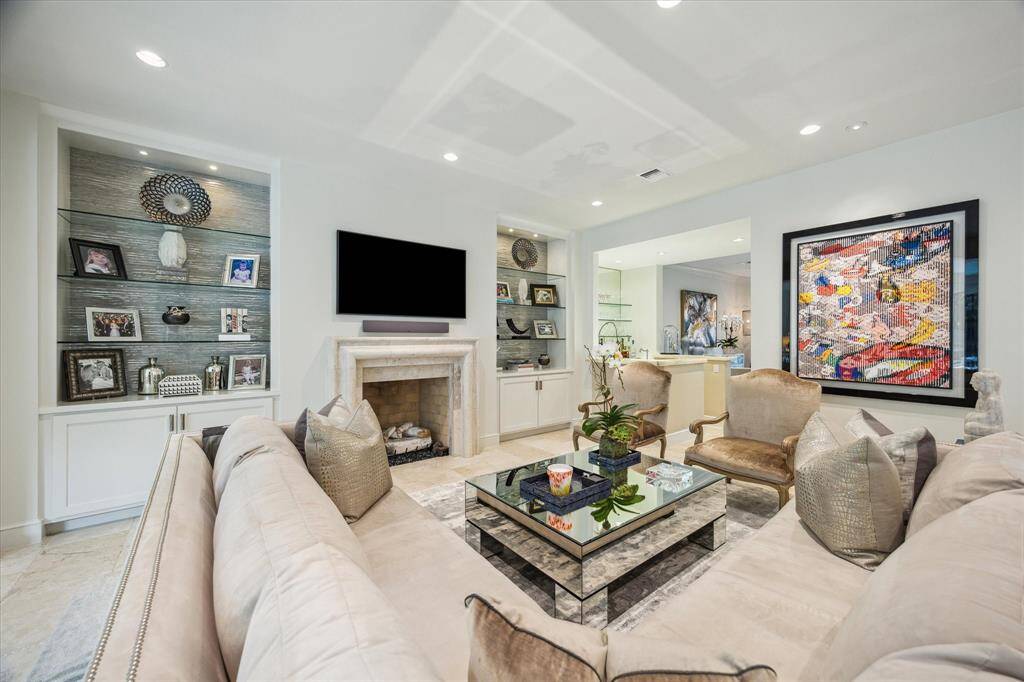 Closer view of the Family Room wall with its handsome centrally placed stone fireplace with built-in cabinets/shelving to display photos and notable items.