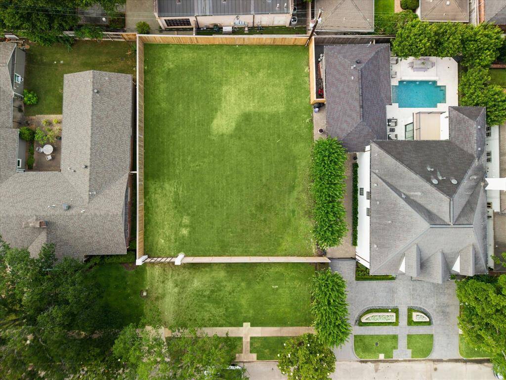 Aerial View of the DOUBLE LOT with the fenced grassed lot to the left and the 6310 sq ft home (per seller) to the right with the front circular drive, driveway, porte-cochere, two car detached garage, main house with adjacent backyard pool with Summer Kitchen, covered/uncovered Living/Sitting areas and lush gardens providing privacy to the space.