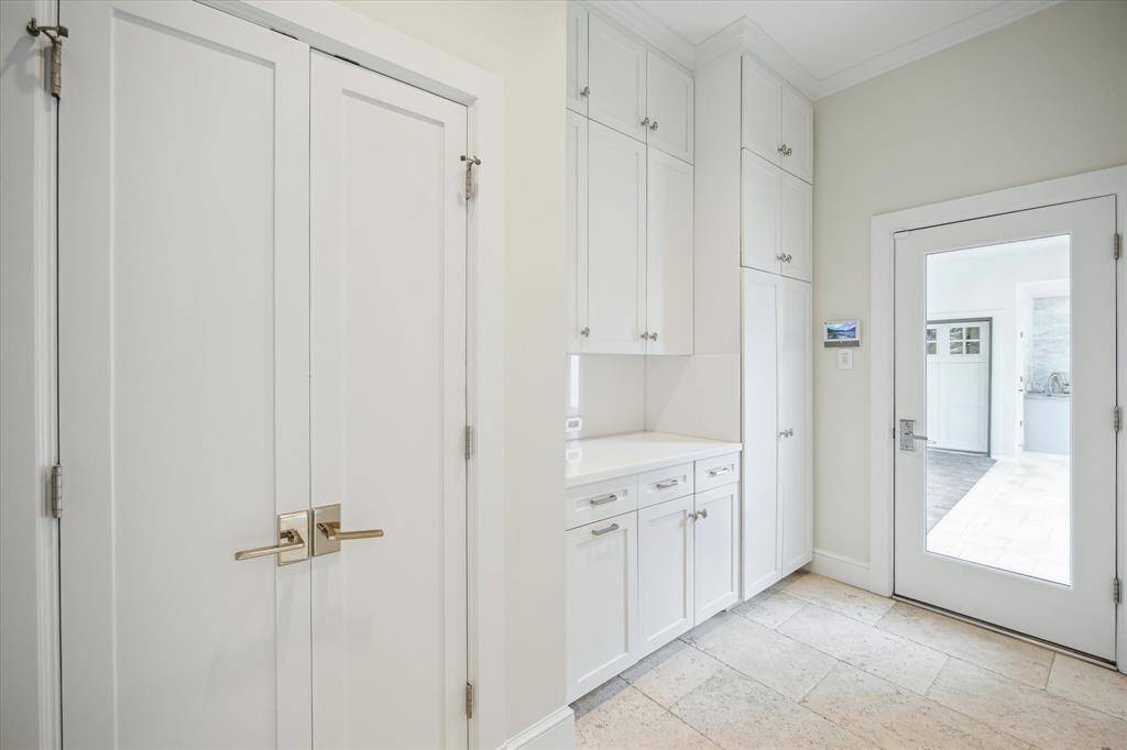 The strategically placed MUD ROOM is just off the Kitchen and opens through the glass door to the Porte-cochere and Garage.  It includes multiple floor to ceiling cabinets/drawers and two utility closets.  Marble counters/backsplash, crown/base molding, travertine tile flooring accentuate the clean lines of the room's design.