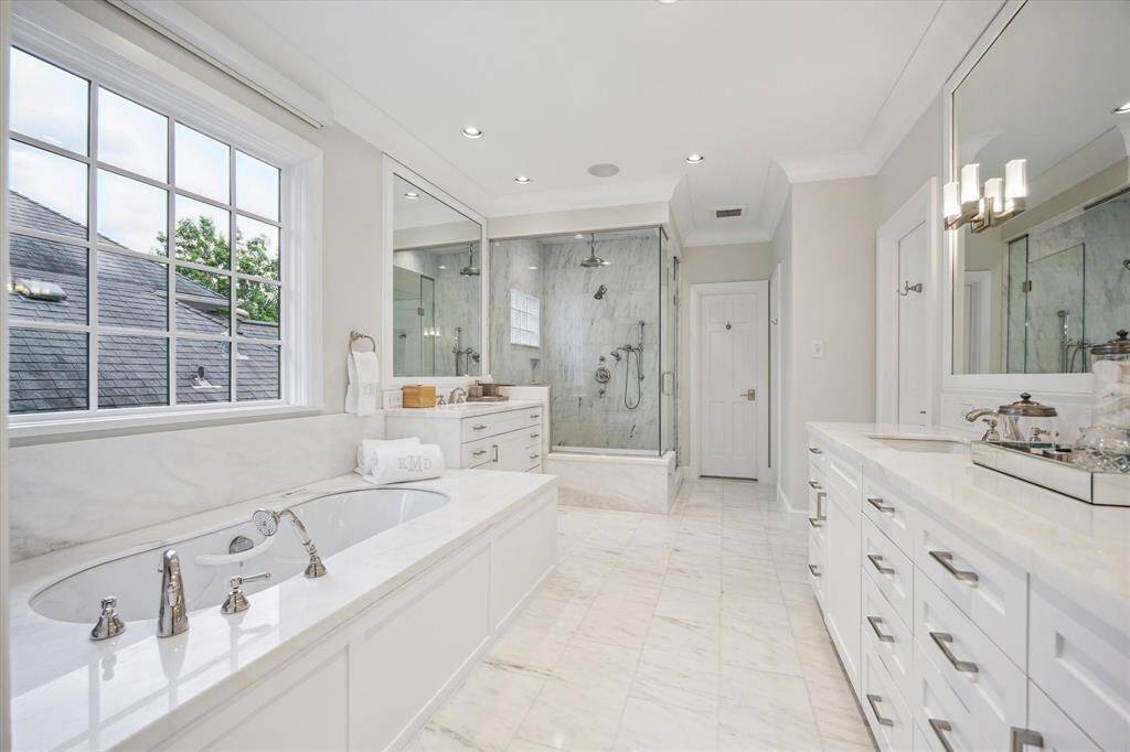 The spacious PRIMARY BATH (17 X 10) is stunning with its marble tile flooring, dual vanities with marble counters/backsplash/cabinets and drawers below, 2 wood framed mirrors, window with privacy shade, ceiling speakers, crown/base molding, private water closet with linen cabinets, Bain Ultra spa tub with marble surround, frameless glass walk-in shower with marble surround/built-in bench/rain head/wand/mosaic tile flooring, two walk in closets.