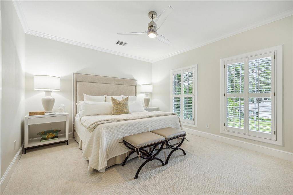 BEDROOM #2 - carpeted flooring, ceiling fan with light, 2 windows with plantation shutters, crown/base molding, walk in closet with shelving and En Suite Bath.