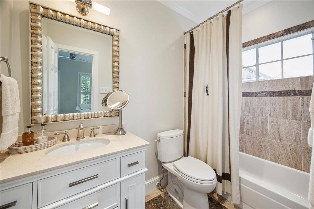 EN SUITE BATH - appointed with tub/shower with granite tile surround, brown marble flooring with decorative tile surround, marble countertop/backsplash, sink with drawers/cabinets below, framed mirror, wall-mounted sconce, recessed lighting, crown/base molding.
