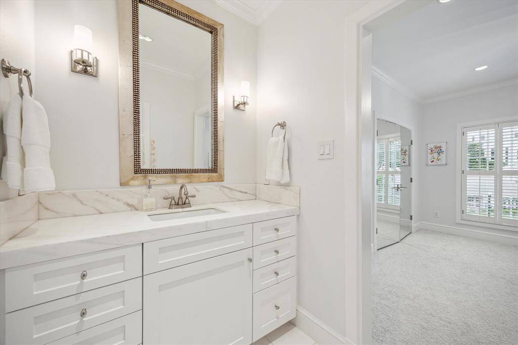 EN SUITE BATH - tub shower with marble surround/hnd wand, white marble tile flooring, white marble countertop/backsplash, sink with cabinet/drawers below, framed mirror, 2 wall-mounted light sconces, recessed lighting, crown/base molding.