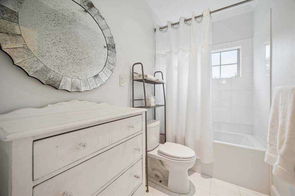 Closer view of the GUEST BATH showing its tub/shower with marble surround, marble flooring and room for a special piece of furniture to finish the space.