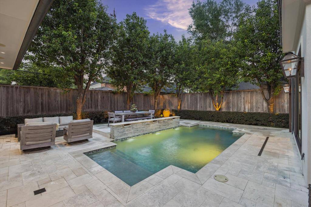Stone tile surrounds the angular shaped, chlorine/heated POOL with its stone wall with decorative 3 water features.  Notice the row of canopied trees along the perimeter fence line - creating further privacy to the outdoor space.