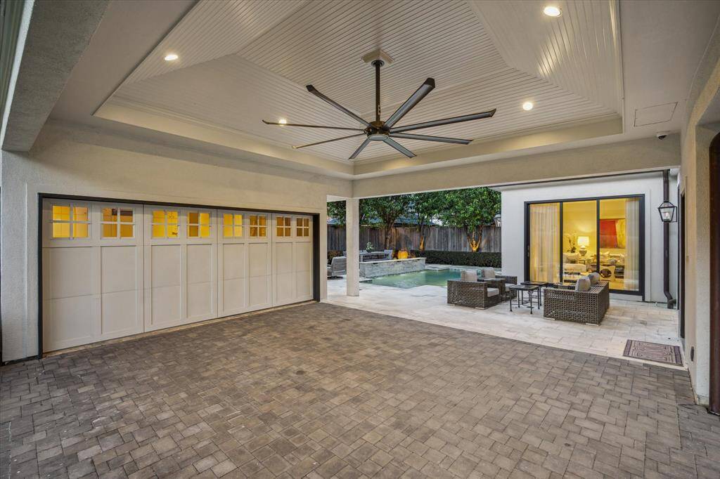 Two Car Carport with extra large ceiling fan, shiplap ceiling, stone pavers, recessed lighting, custom garage doors.  Not seen is the driveway gate.