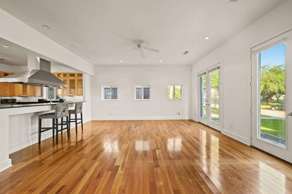 Wood floors throughout living room and window coverings over French doors.