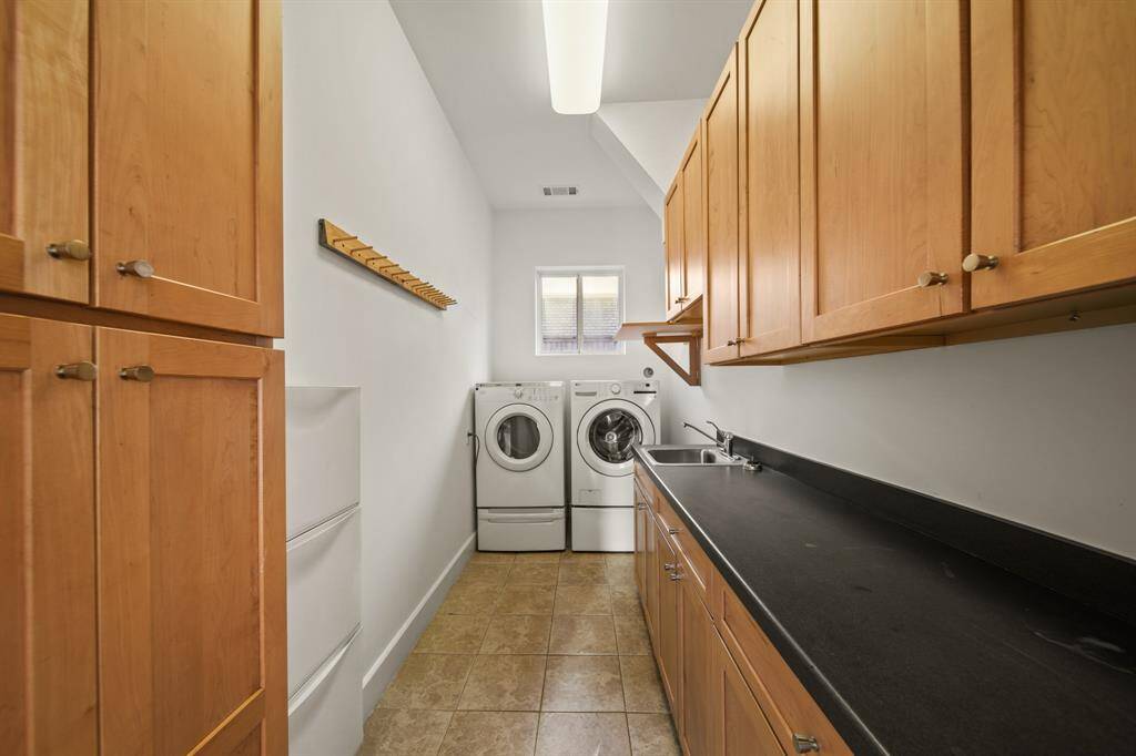 Utility room with plenty of cabinets, counter space and utility sink.