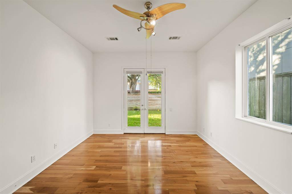 Bedroom with wood floors, contemporary fan and French doors allowing access to backyard and windows to allow for natural light.