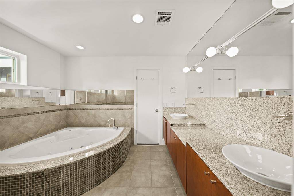 Primary bathroom with granite counters and soaking tub with dual sinks.