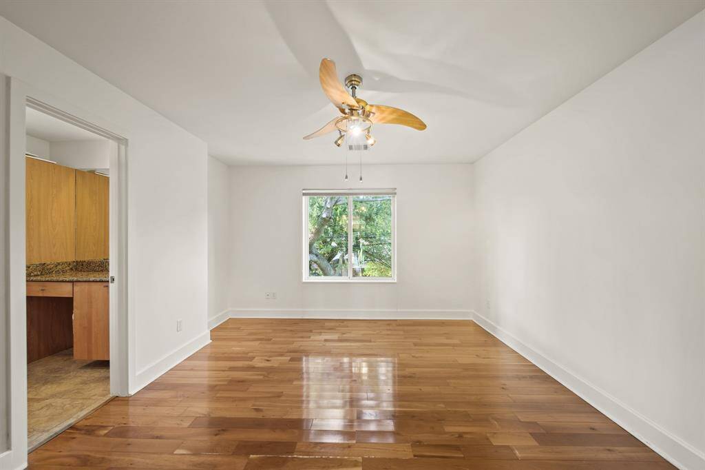 Bedroom with wood floors, modern fan fixture and attached full bathroom access.