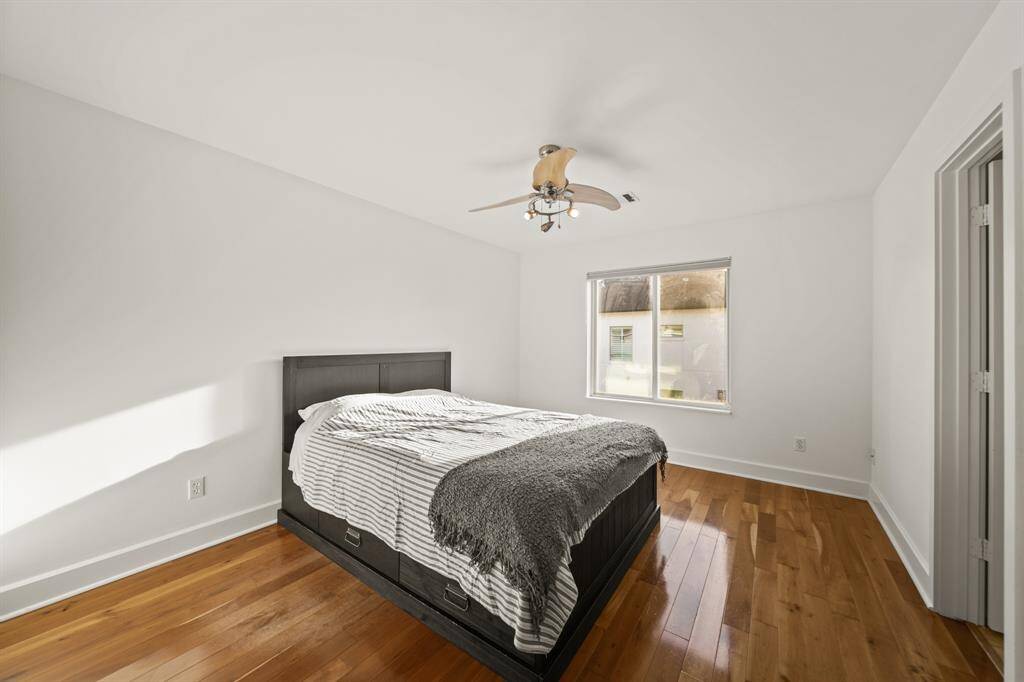 Bedroom with wood floors, contemporary fan and attached bathroom.