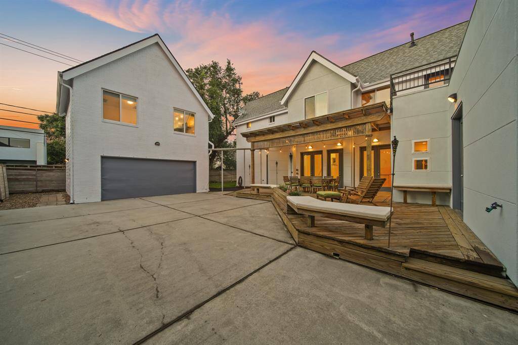 View of 2 car detached garage with second floor guest quarters and view of back patio with additional seating area.
