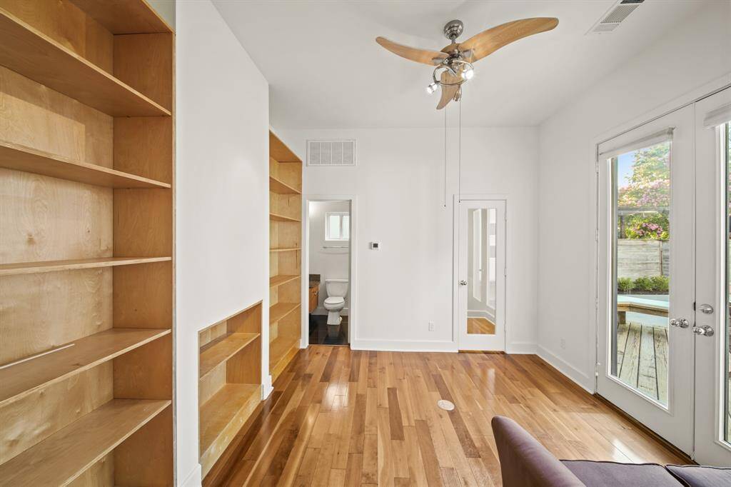 Bedroom/study/flex room with built ins, closet, and access to full bathroom. Wood floors, ceiling fan and French doors allow for natural sunlight to shine through the windows and doors.