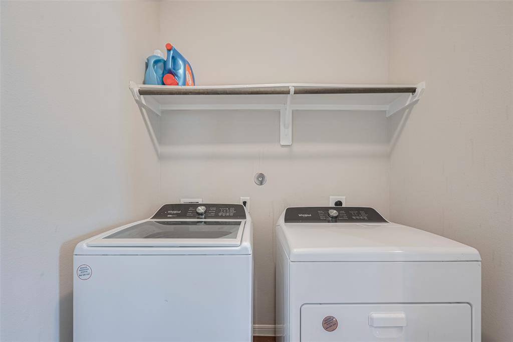 This laundry space includes ample room for full-sized appliances, plus open shelving for everyday convenience.