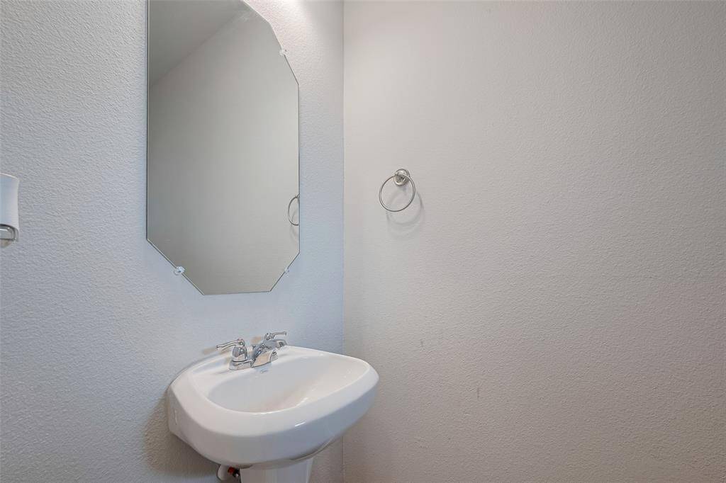 Simple and stylish, the half bath features a clean pedestal sink and a frameless mirror that reflects the room’s soft lighting.