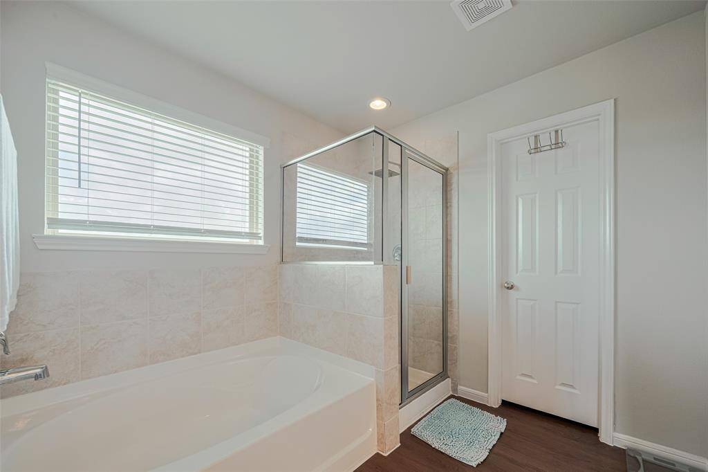 The side-by-side tub and shower are framed by tastefully tiled walls, with the tub perfectly positioned beneath a sunny window.