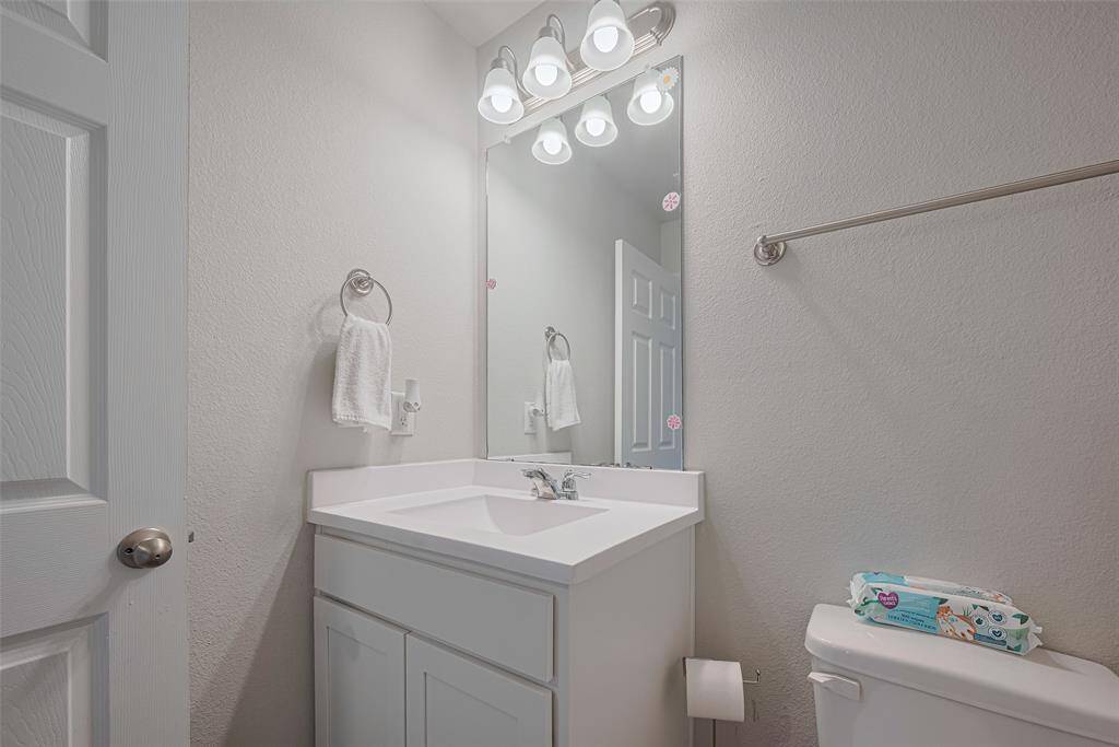 The vanity and glowing mirror lend an uplifting feel to the secondary bathroom, blending form and function.