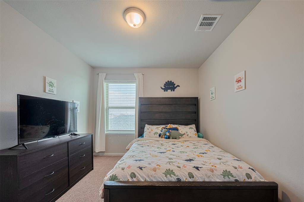 Soft carpeting, surface-mount lighting, and a generous window make this additional bedroom feel inviting and tranquil.