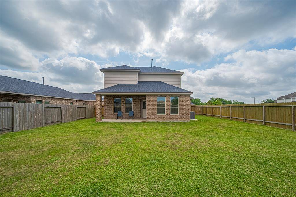A wide-angle view of the home’s back exterior shows its inviting covered patio and expansive lawn beyond.