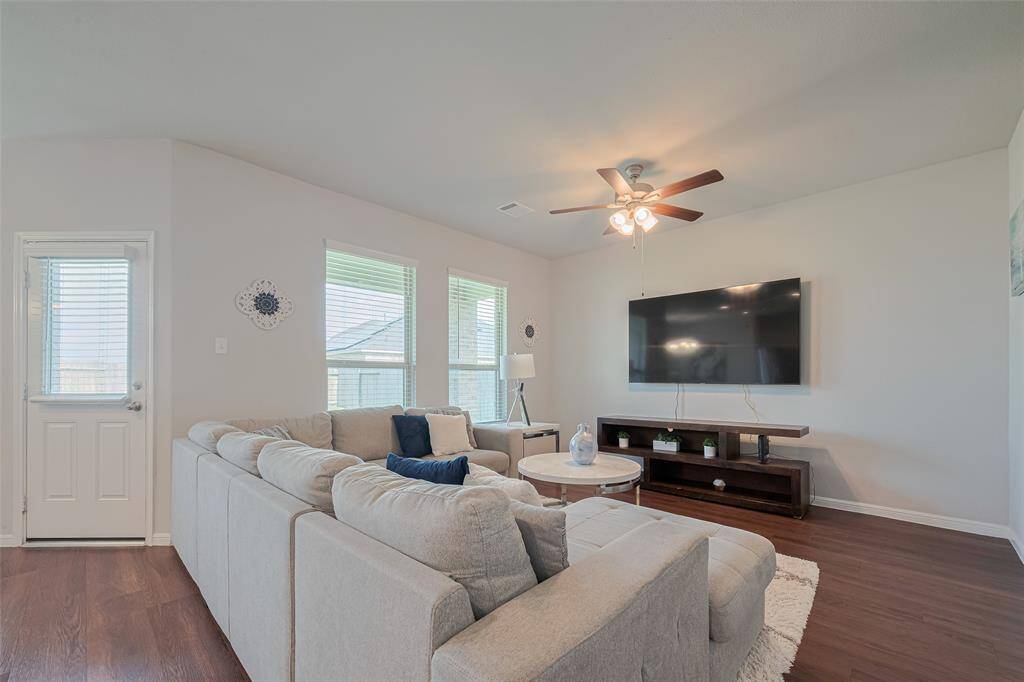 Framed by large windows and centered beneath a ceiling fan, this living space is designed for everyday comfort.