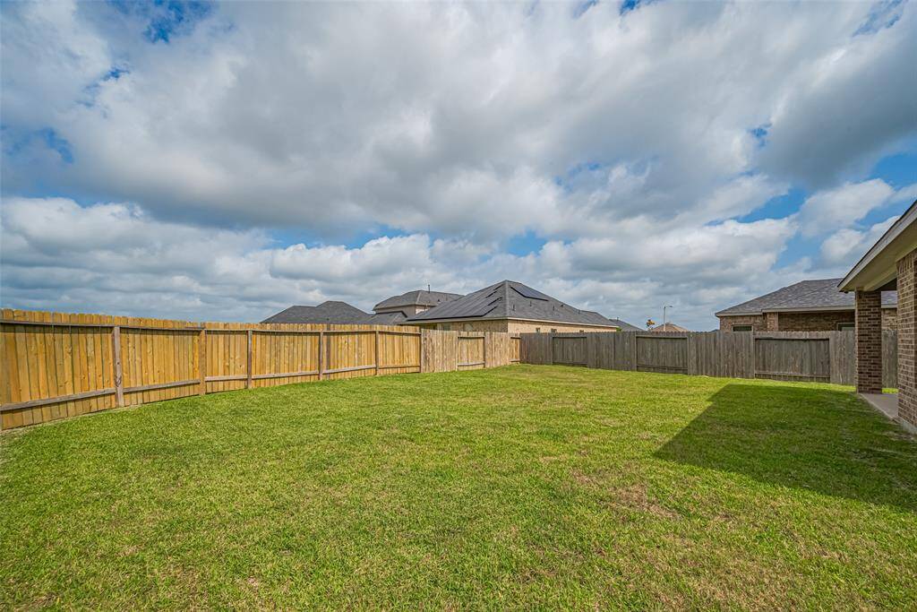 A second backyard perspective highlights the open space and grassy stretch that frames the back of the home.