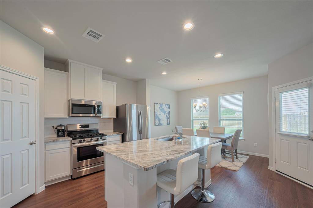 Clean lines and open sightlines draw you into the heart of the home, where the kitchen opens up to a sunny dining nook.