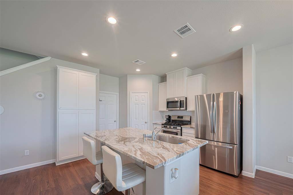 Crisp white upper and lower cabinets provide generous storage and elevate the kitchen’s bright, fresh aesthetic.