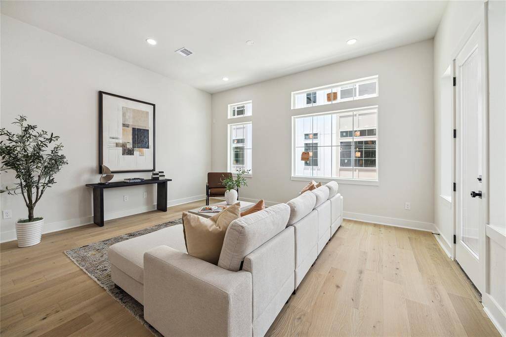 Bright and inviting living room with large windows, modern decor, and beautiful wood floors—perfect for relaxation and entertaining.