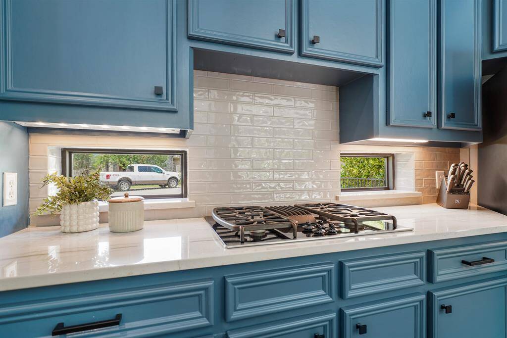 The Kitchen is equipped with GE Profile appliances, including this 4-burner, gas cooktop. A pair of countertop windows provide additional natural light to your prep space.