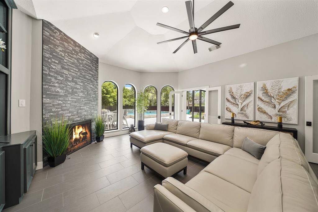 This spacious Den boasts a vaulted ceiling, 8-blade, oversized fan, and a quartet of arched picture windows overlooking the Backyard oasis and Pool. A pair of glass-plated French doors separate the space from the Family Room and Formal Dining beyond.