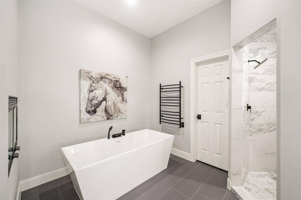 Wash away the stress of the day in this oversized, floor-to-ceiling tiled shower with dual showerheads. Care to stay awhile? Unwind in the comfort of this large, free standing tub with heated towel rack while enjoying the warmth from the dual-sided fireplace above. The space also boasts two spacious, walk-in closets with custom built-ins.