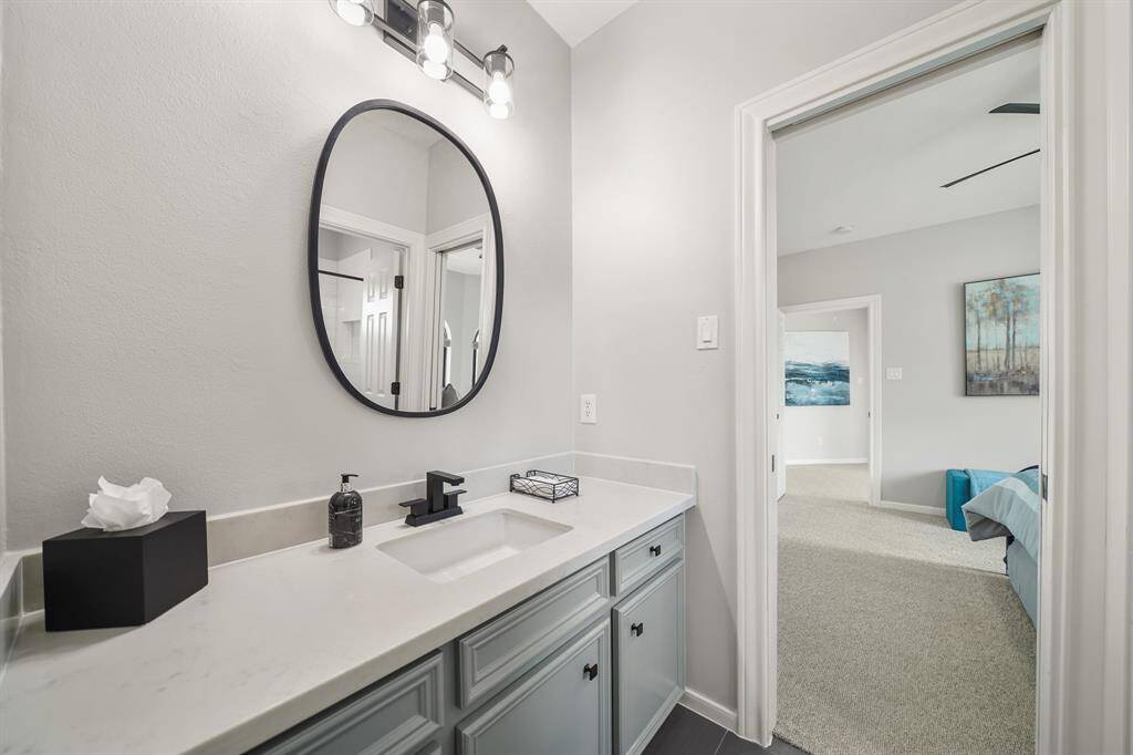 This Secondary Bathroom is accessible from both the Game Room and one of the three Secondary Bedrooms upstairs. The space includes an undermount sink, quartz countertop, matte black hardware, framed mirror, and subway tiled shower/tub combo.