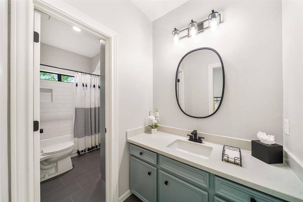 The previously seen Bedroom has direct access to this Jack and Jill Bathroom. This view offers a peek of the subway tiled shower/tub combo with transom windows above.